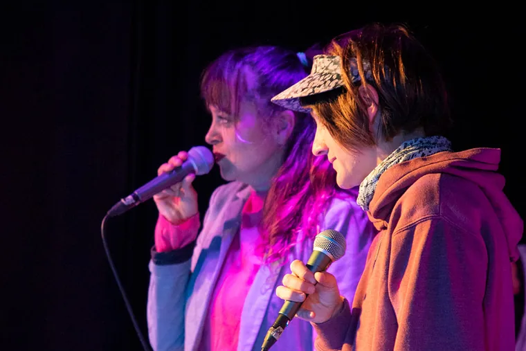 Zwei Performerinnen teilen sich die Bühne und halten Mikrofone