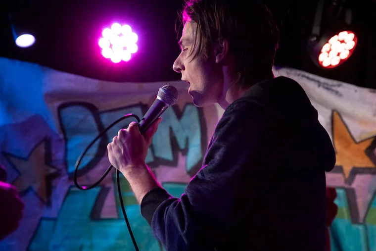 Performerin mit Mikrofon im violetten Bühnenlicht
