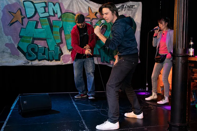 Rapper in Bewegung vor einer Gruppe auf der Bühne